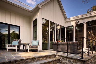 Outdoor patio with striped seating and stone pavers in a custom home in Charlotte, NC by Simonini Homes
