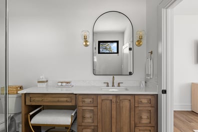 Double vanity bathroom with natural wood cabinets and arched mirror by Simonini Homes in Mooresville, NC
