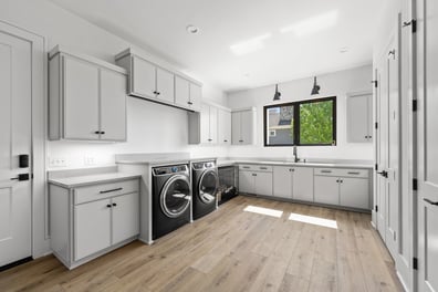 Modern laundry room with white cabinetry and wood flooring in a custom Mooresville, NC home by Simonini Homes
