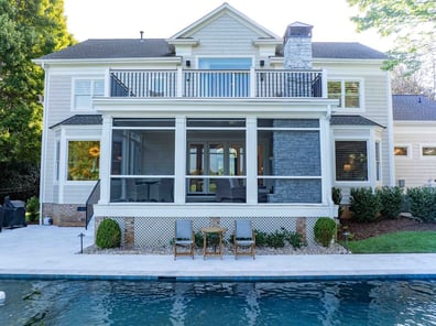 Back view of home with stone fireplace, porch, and pool from a renovation in Ballantyne, NC