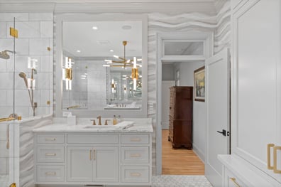 Bright marble bathroom with gold hardware and custom storage in a renovation in Ballantyne, NC