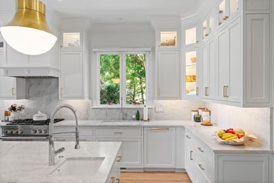 Bright white kitchen with marble countertops and double window from a renovation in Ballantyne, NC