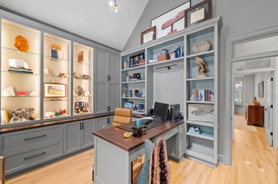 Home office with custom gray built-ins and mineral display from a renovation in Ballantyne, NC