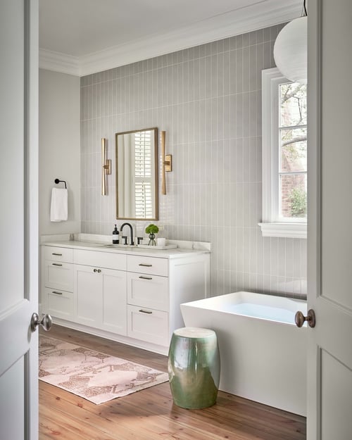 Elegant bathroom with freestanding tub and vertical tile accent wall in Charlotte home by Simonini Homes