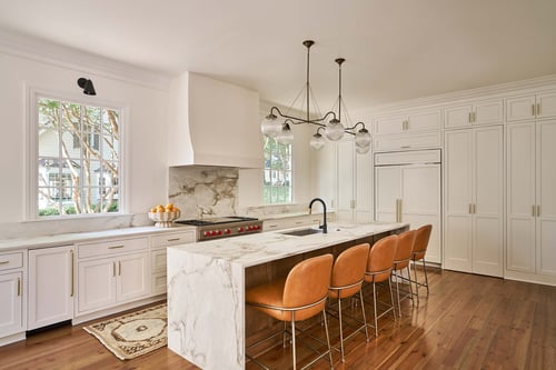 Elegant white kitchen with marble counters and modern lighting in Charlotte custom home by Simonini Homes