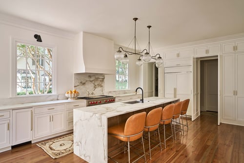 Spacious Charlotte kitchen with leather barstools and white cabinetry by Simonini Homes