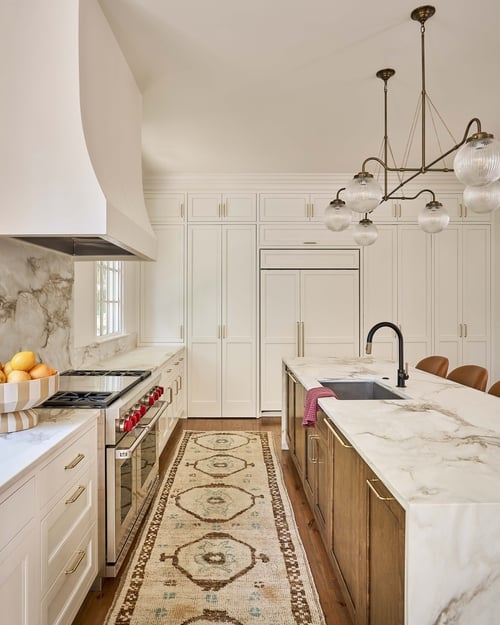 View of Charlotte custom kitchen with marble counters, statement rug, and luxury appliances by Simonini Homes