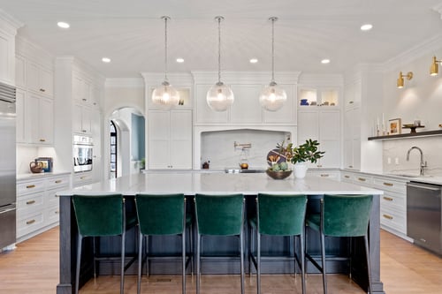 Full view of transitional kitchen with white cabinetry and green bar stools in a custom home in Charlotte, NC