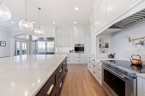 Kitchen interior with oversized marble island and pendant lights in a custom home in Charlotte, NC