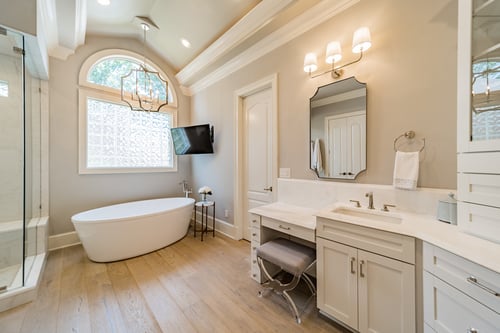 Freestanding bathtub under arched window and chandelier in a custom home in Charlotte, NC