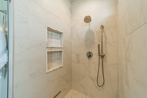 Marble tile walk-in shower with built-in niches in a custom home in Charlotte, NC