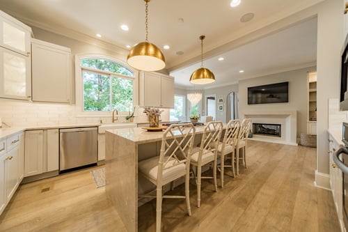 White kitchen island with seating and brass lighting in a custom home in Charlotte, NC