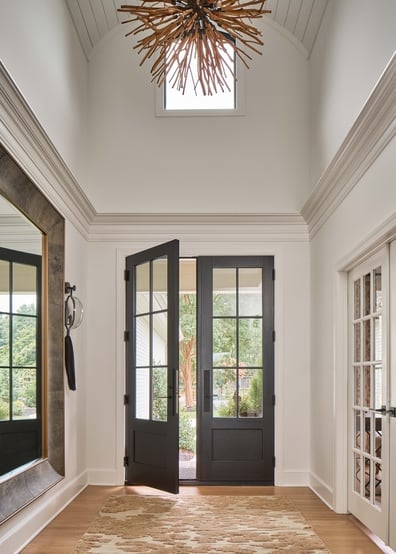 Vaulted entryway with double glass doors and modern chandelier in a custom home by Simonini Homes in Charlott