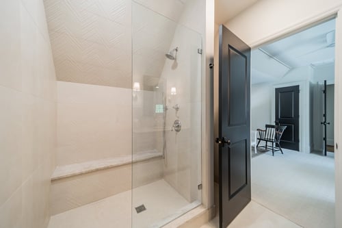 Glass-enclosed shower with textured tile and bench seating in a Charlotte, NC renovation