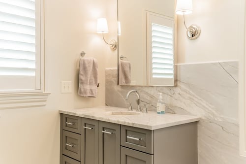 Gray bathroom vanity with marble countertop and chrome fixtures from a renovation in Charlotte, NC