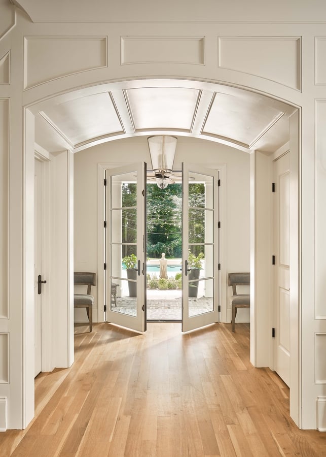 Arched hallway entry with French doors opening to a backyard in a Charlotte custom home by Simonini Homes