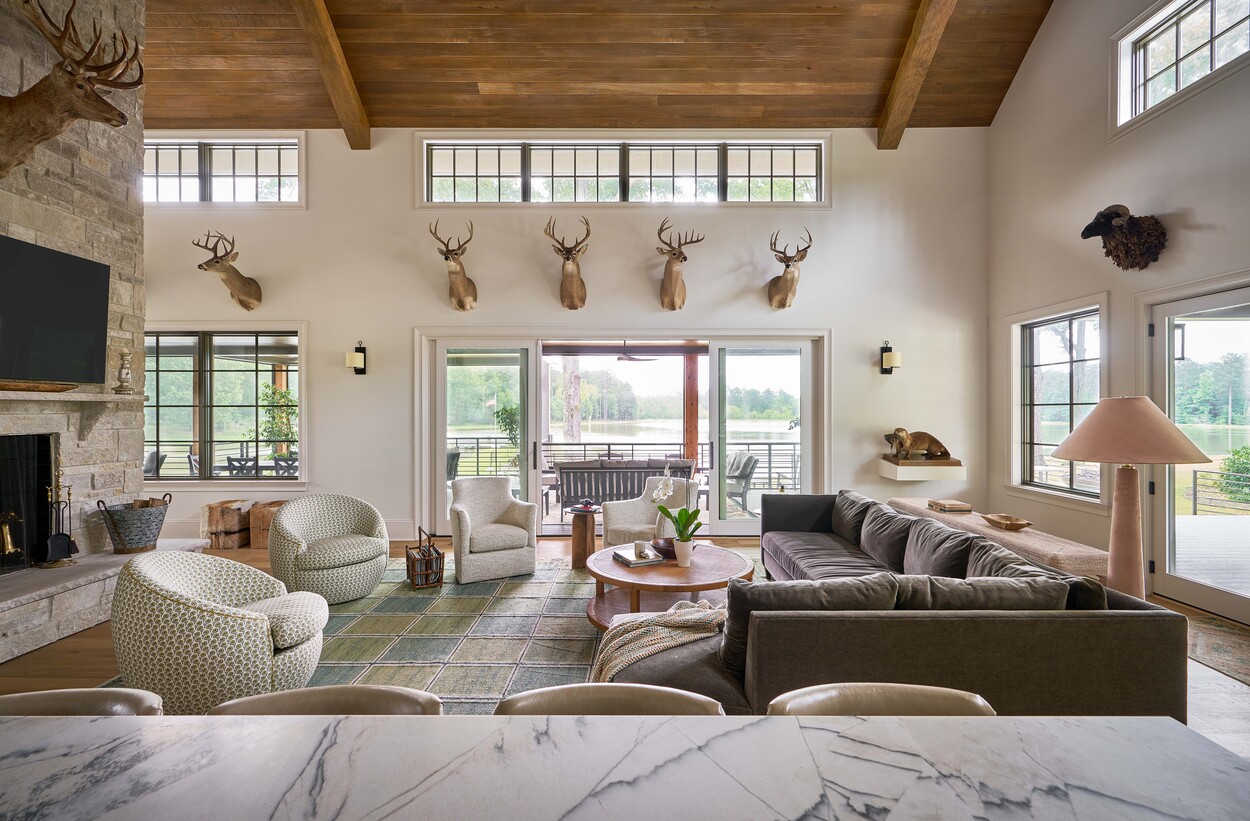 Cozy lodge living room with taxidermy mounts and lake view at Custom Hunting Lodge in Fort Lawn, NC by Simonini Homes.-1
