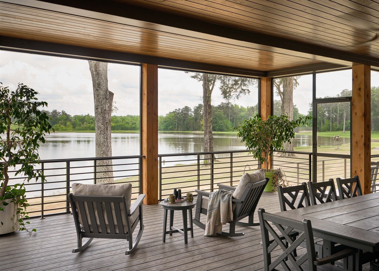 Serene porch view with rocking chairs overlooking lake at Custom Hunting Lodge in Fort Lawn, NC by Simonini Homes-1
